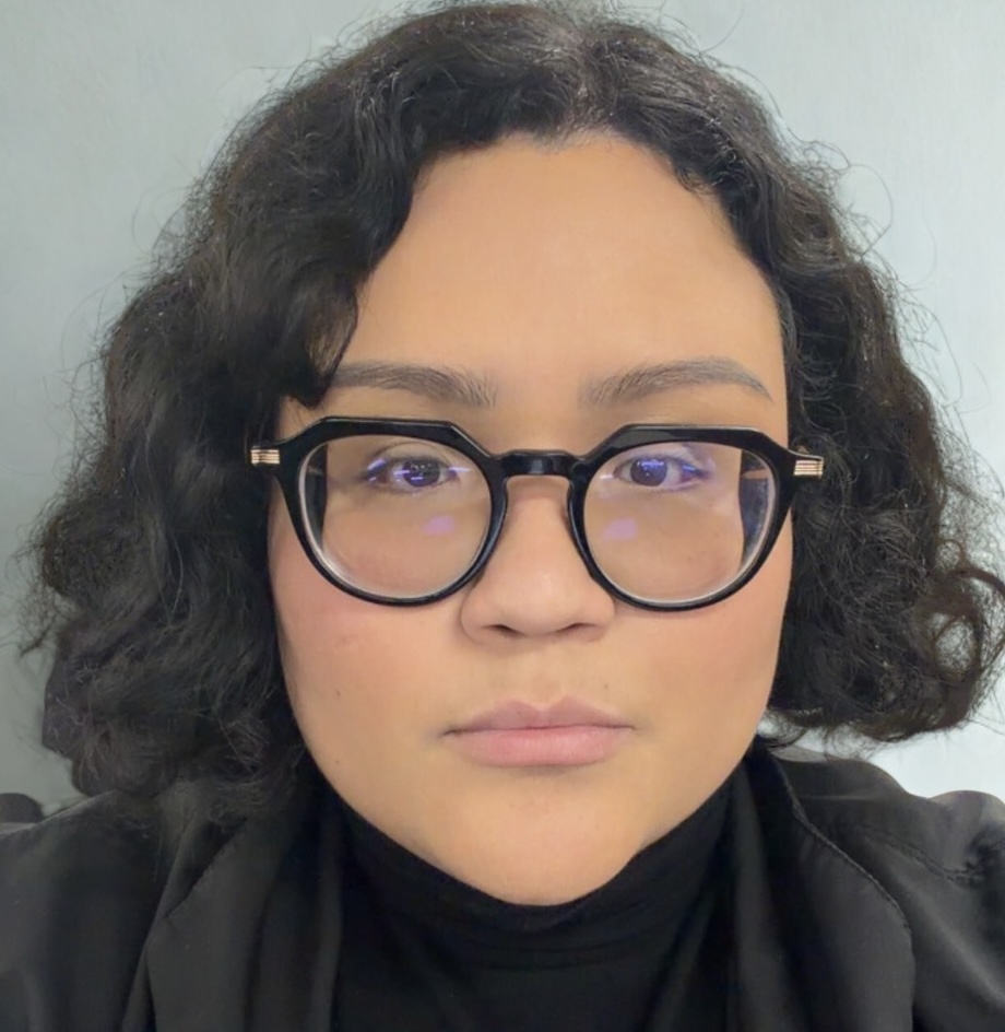 Giselle Garcia, a person with short wavy black hair and glasses, looks at the camera.